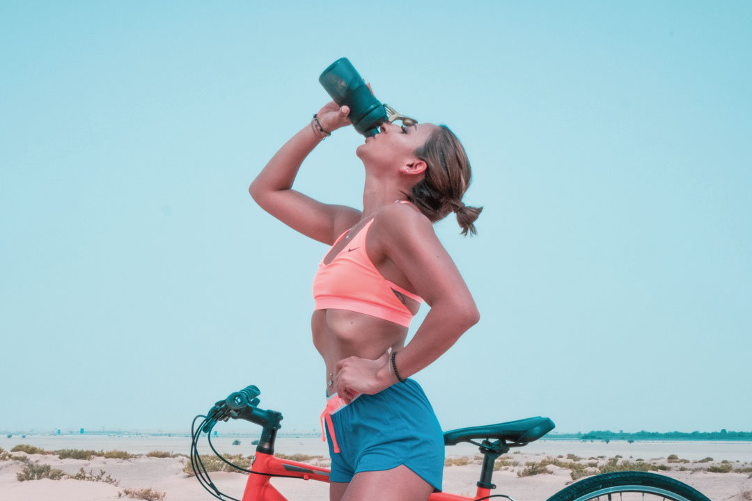 Chica Bebiendo Agua Sobre una Bici