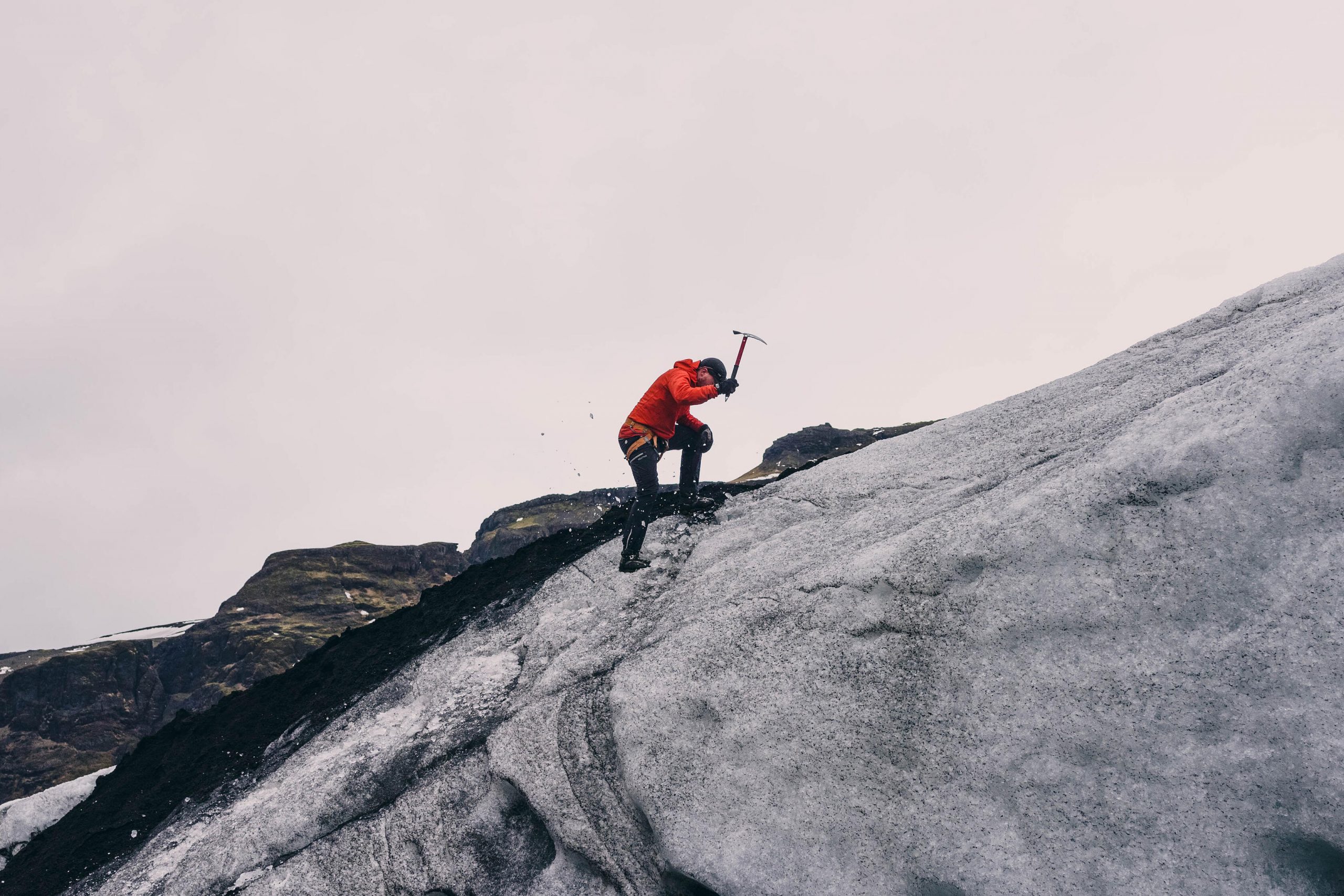 Alpinista ascendiendo una montaña con un piolet - Material de alpinismo