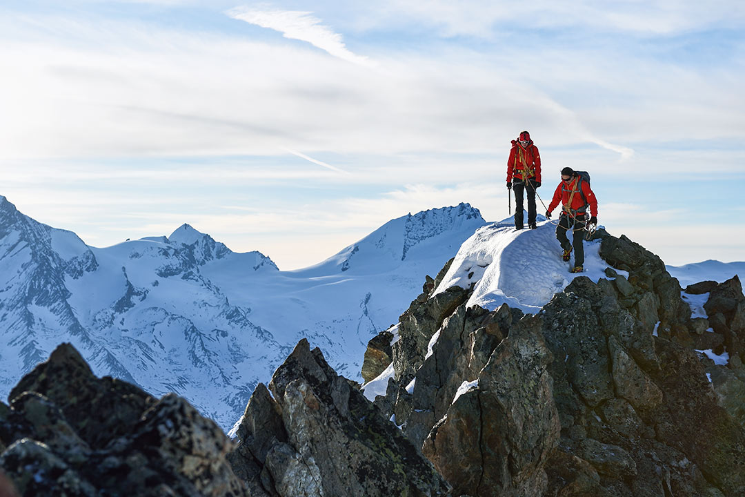 Dos alpinistas con chaqueta roja en la cresta de una montaña - Preparación para alpinismo 