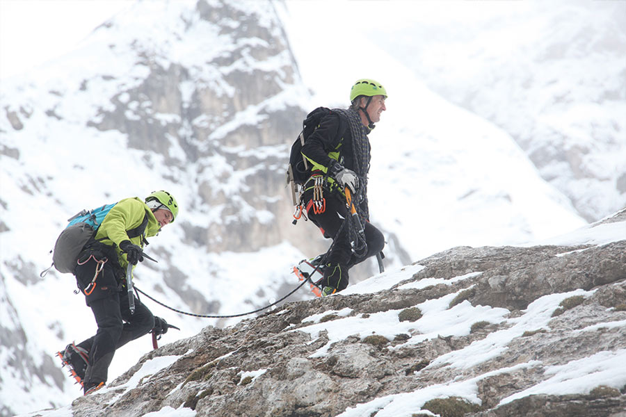 Dos alpinistas con cuerda, piolet y casco verde
