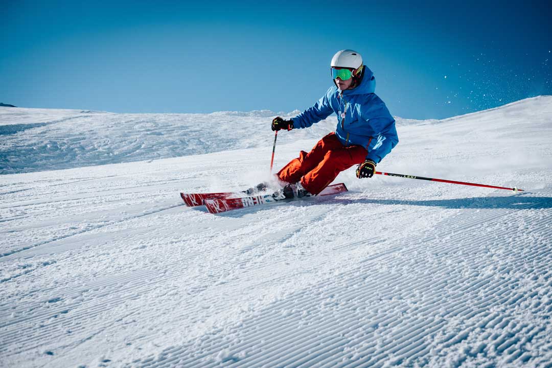 Hombre con ropa deportiva brillante esquiando en la zona de montaña